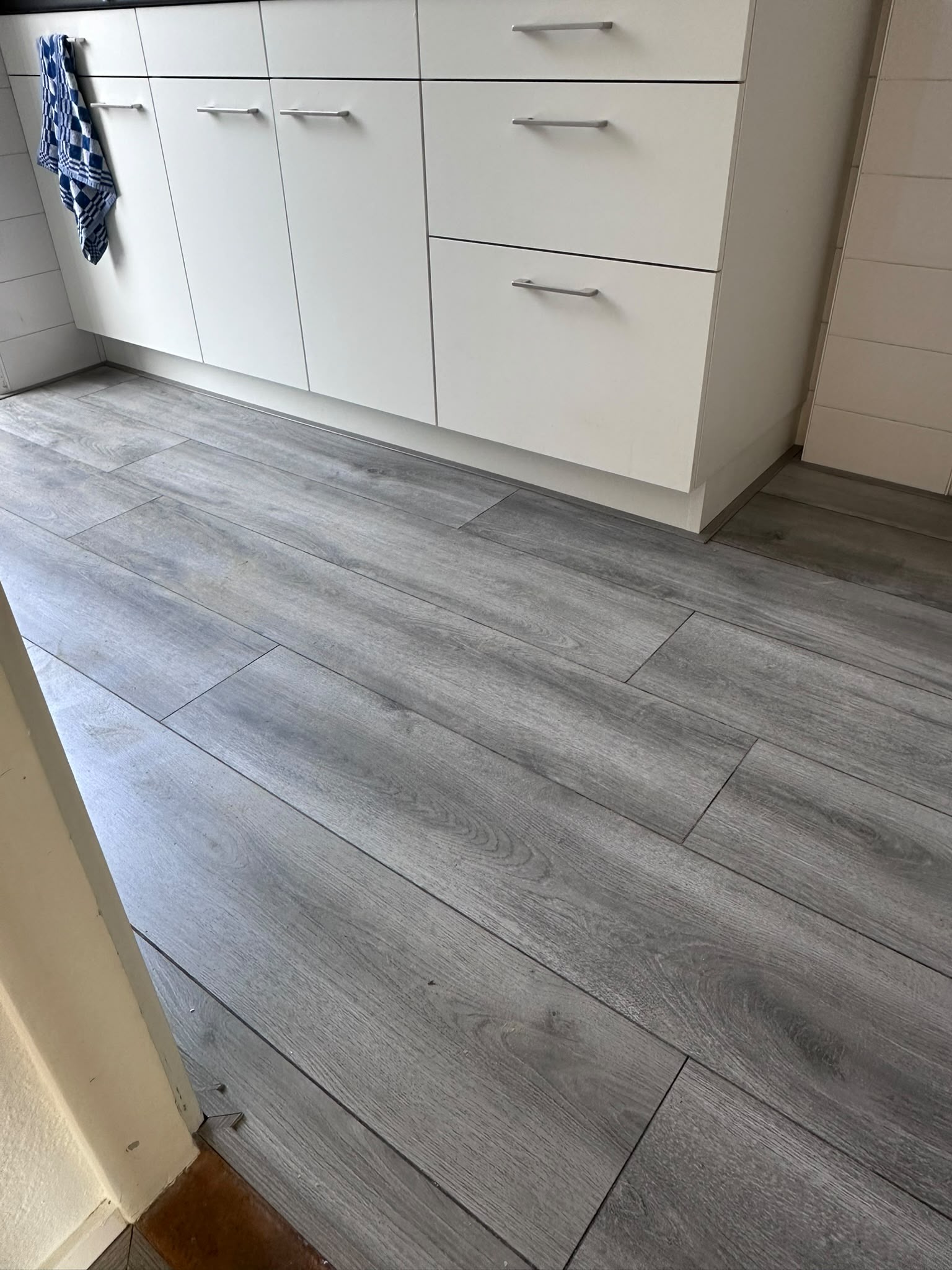Grijze vloer met houtlook planken naast een keukenkast